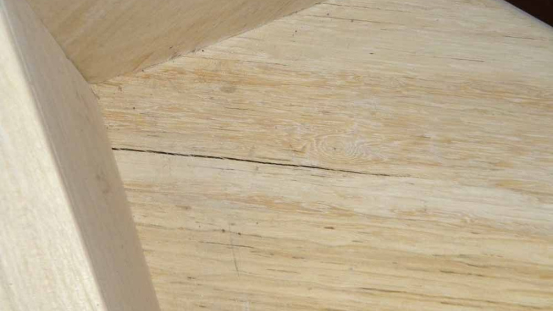 Fissure visible sur une marche d'escalier en bois, prête à être réparée avec de la pâte à bois.
